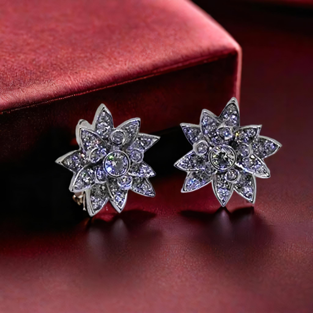 Paire de boucles d’oreilles en forme de fleurs étoilées, serties de diamants, posées sur un fond en velours rouge